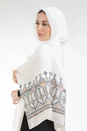 The Shamadan Ivory Candlestick Tatreez Shawl is a soft, breathable embroidered hijab made from crepe fabric with delicate detailing—ideal for daily wear and special occasions.
