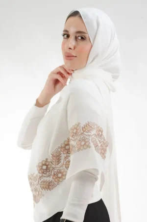 The Pine Ivory Tatreez Shawl is a cozy, well-ventilated embroidered hijab made from crepe fabric with meticulous handiwork—great for day-to-day wear and celebrations. شال تطريز شجرة الصنوبر اوف وايت من فلاحي هاوس بتصميم شجرة الصنوبر هو حجاب مطرز ومريح وجيد التهوية مصنوع من قماش الكريب مع براعة يدوية دقيقة، رائع للارتداء اليومي والمناسبات.