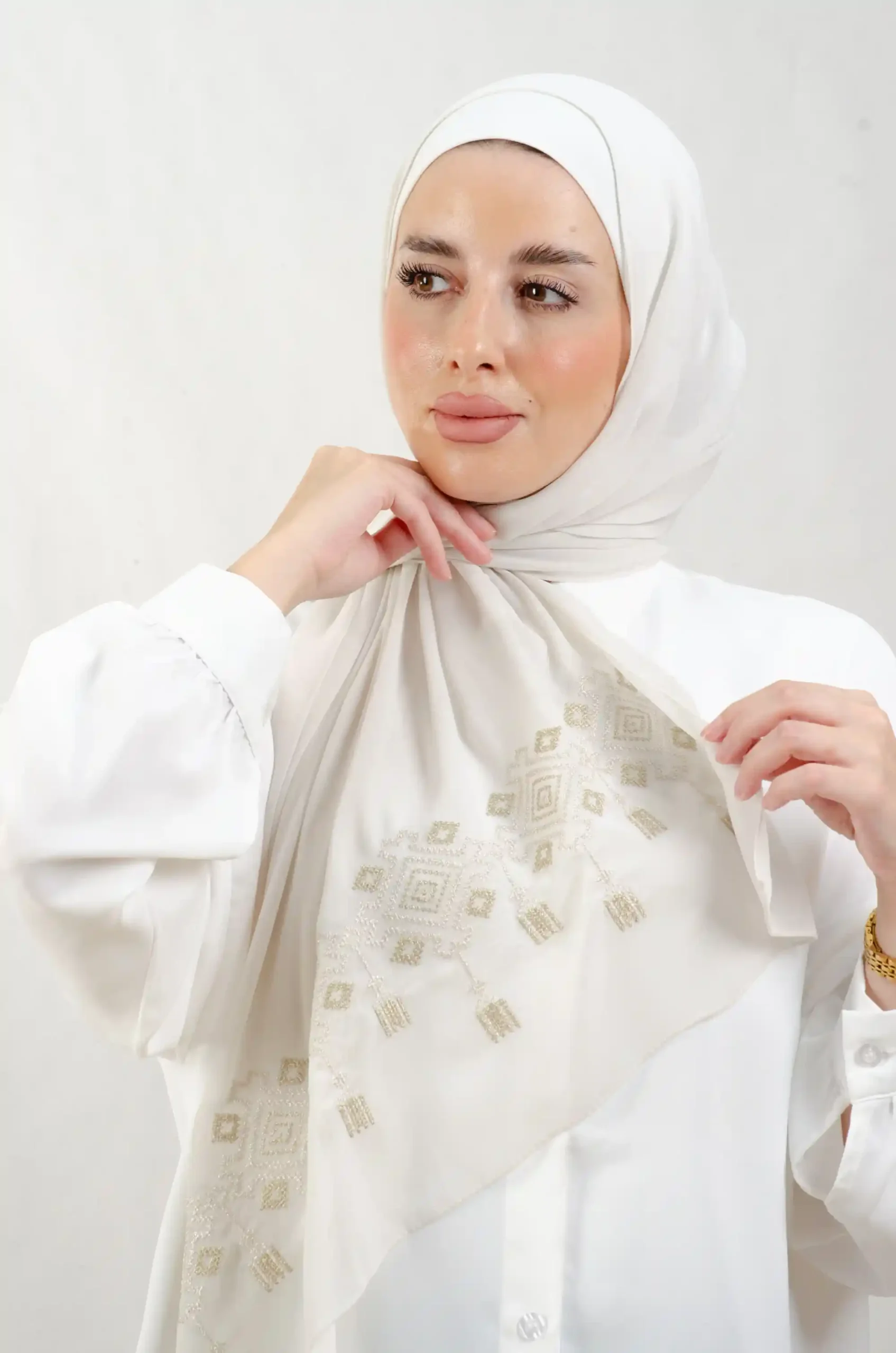The Chandeliers Metal Tatreez Shawl is a cozy, breathable embroidered hijab made from Georgette chiffon fabric. Perfect for everyday wear and celebrations. شال تطريز عاجي ثرية ميتاليك من فلاحي هاوس بتصميم ثريات باللون العاجي هو حجاب مطرز ومريح وجيد التهوية مصنوع من قماش الشيفون جورجيت. مثالي للارتداء اليومي والمناسبات.