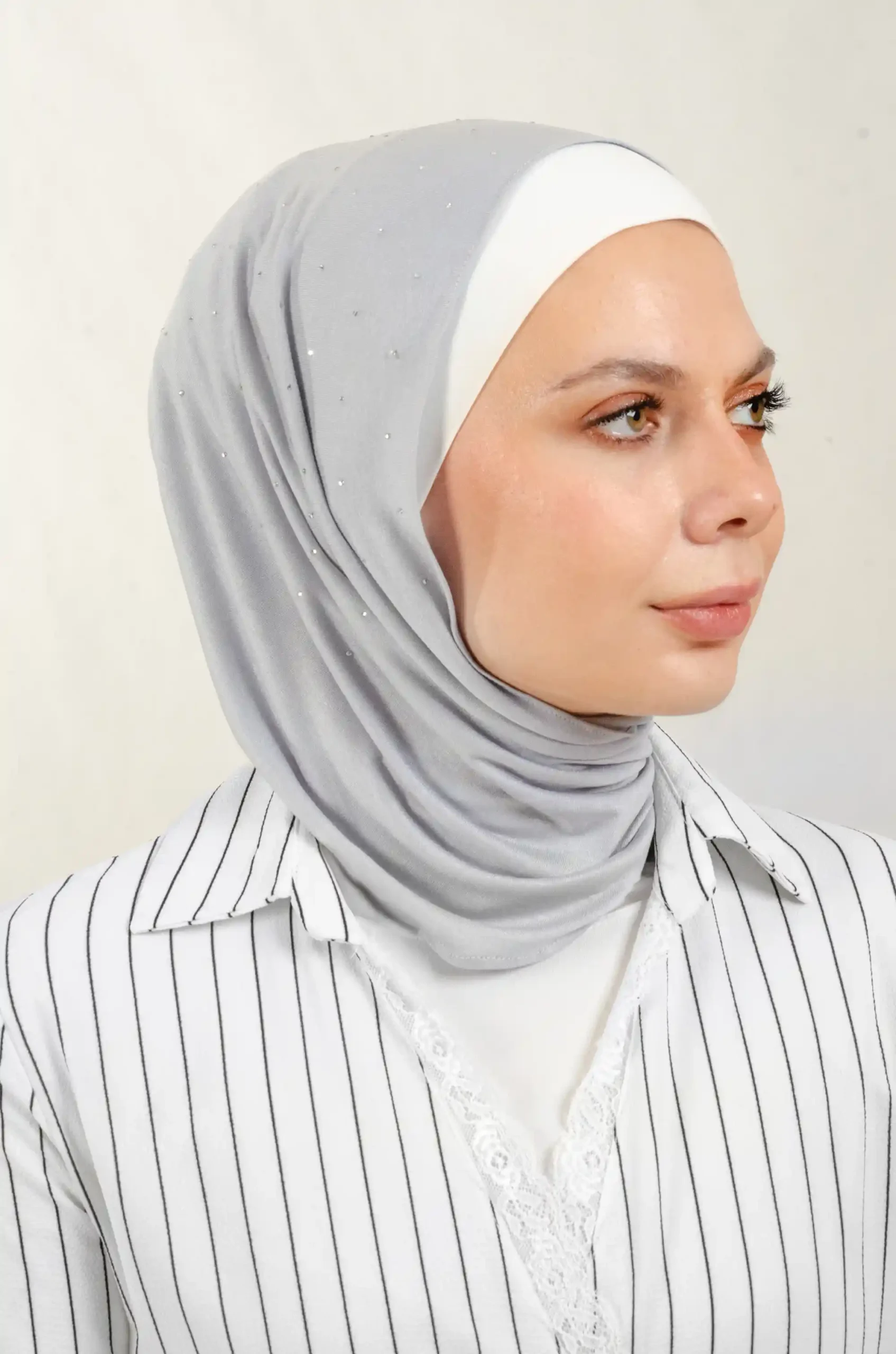 The DMC Strass Dots Grey Tiangle Shawl is a cozy, breathable triangle hijab made from cotton fabric with shimmering Strass details in grey. Perfect for both daily wear and special occasions.