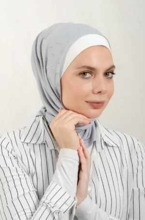 The DMC Strass Larva Grey Triangle Shawl is a cozy, breathable triangle hijab made from cotton fabric with shimmering Strass details in grey. Perfect for both daily wear and special occasions.