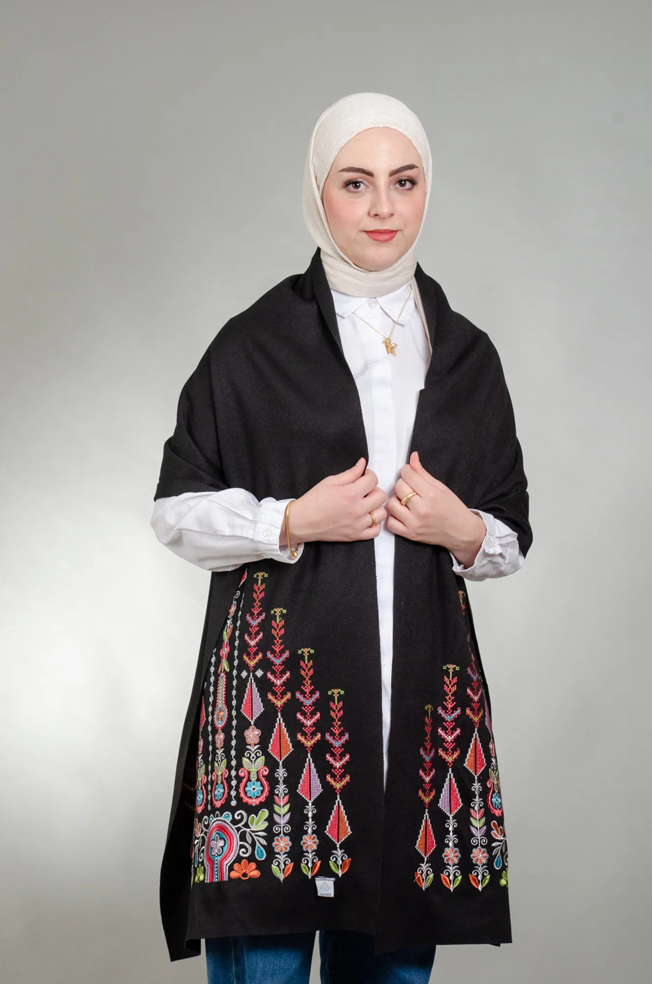Model wearing black Al-Saa'ah with Al-Sarw Candy Mix shoulder shawl with coral, pink and lilac cypress embroidery