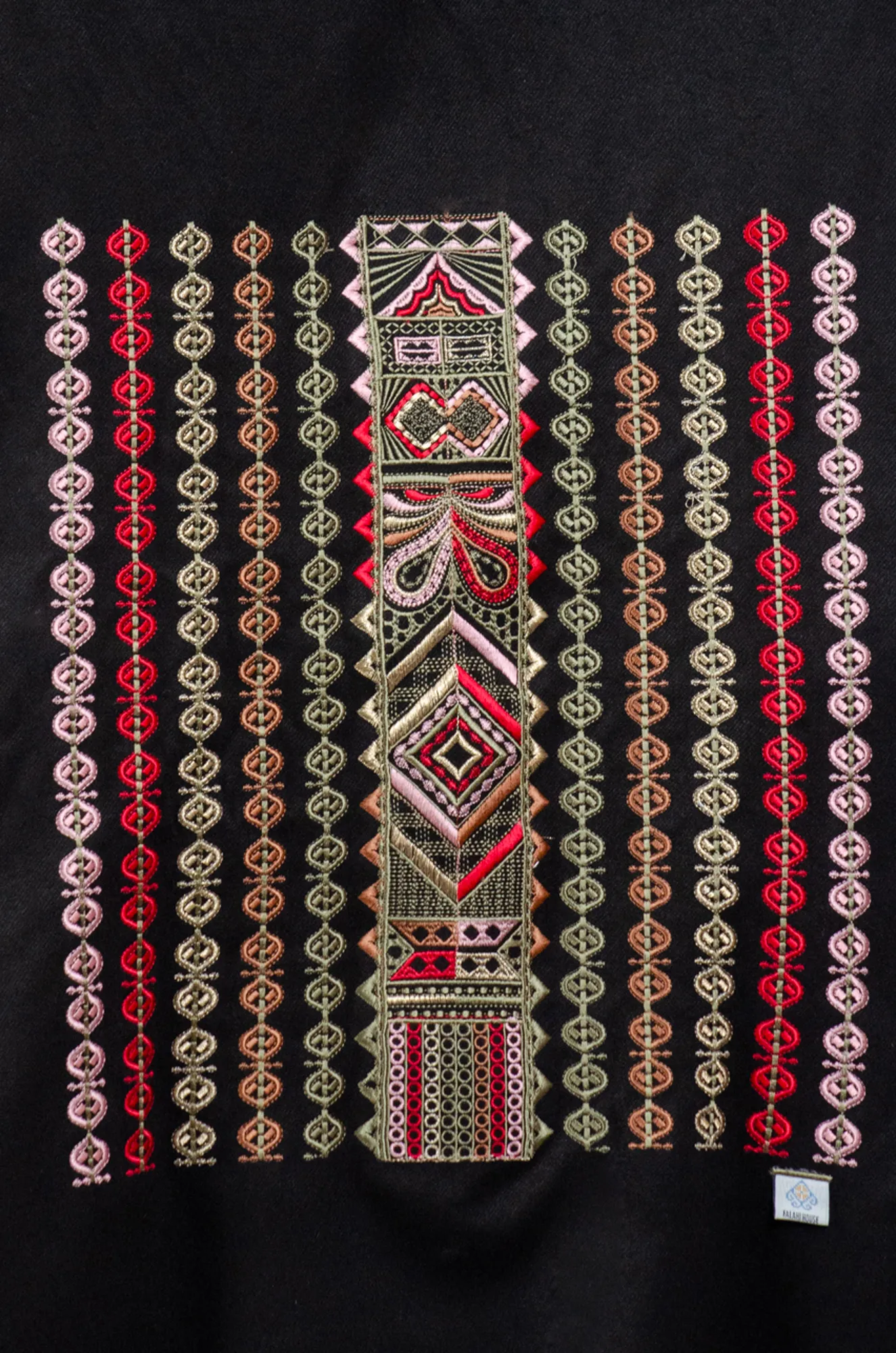 Close-up of olive, red and copper Al-Shamal Bratto embroidery on black shoulder shawl