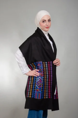 عارضة ترتدي شال كتف الشمال نيلي ميكس أسود بتطريز فلاحي بالأزرق والخردلي والأحمر والبنفسجي